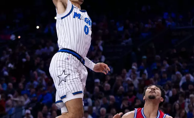 Orlando Magic's Anthony Black (0) goes up for the dunk as Philadelphia 76ers' Jared McCain (20) looks on during the first half of an NBA Cup basketball game, Tuesday, Nov. 25, 2025, in Philadelphia. (AP Photo/Chris Szagola)