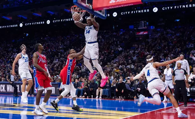 Orlando Magic's Wendell Carter Jr. (34) dunks the ball after taking the pass from Jalen Suggs (4) with Philadelphia 76ers' Jabari Walker, center left, defending during the first half of an NBA Cup basketball game, Tuesday, Nov. 25, 2025, in Philadelphia. (AP Photo/Chris Szagola)