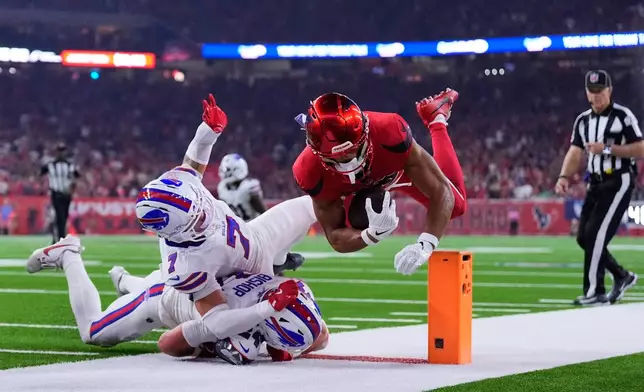 Houston Texans wide receiver Xavier Hutchinson, right, is tackled by Buffalo Bills' Taron Johnson (7) and Cole Bishop (24) in the first half of an NFL football game Thursday, Nov. 20, 2025, in Houston. (AP Photo/Ashley Landis)