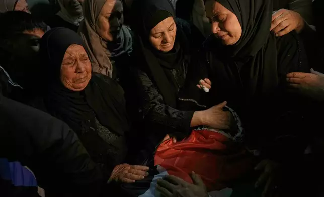 Palestinian women mourn over the body of Jamil Hanani, 17, who, according to health authorities, was killed after being shot in the chest during an Israeli raid, at his funeral in the West Bank village of Beit Furik, Monday, Nov. 3, 2025. (AP Photo/Majdi Mohammed)