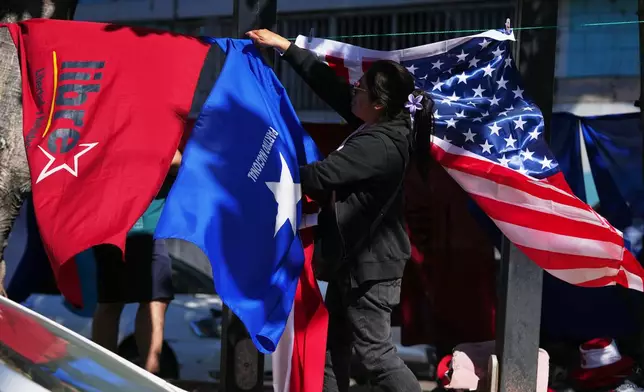 A street vendor hangs flags representing the National Party LIBRE, from left, the National Party, and the United States, near the national stadium in Tegucigalpa, Honduras, Saturday, Nov. 29, 2025, a day ahead of the general election. (AP Photo/Moises Castillo)