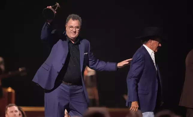 Vince Gill accepts the lifetime achievement award during the 59th Annual Country Music Association Awards on Wednesday, Nov. 19, 2025, at Bridgestone Arena in Nashville, Tenn. George Strait looks on from right.(AP Photo/George Walker IV)
