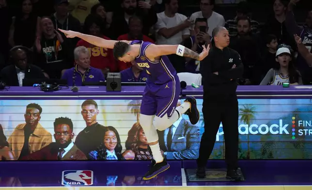 Los Angeles Lakers guard Luka Doncic celebrates his three-point basket past Los Angeles Clippers head coach Tyronn Lue during the first half of an NBA Cup basketball game Tuesday, Nov. 25, 2025, in Los Angeles. (AP Photo/Jae C. Hong)