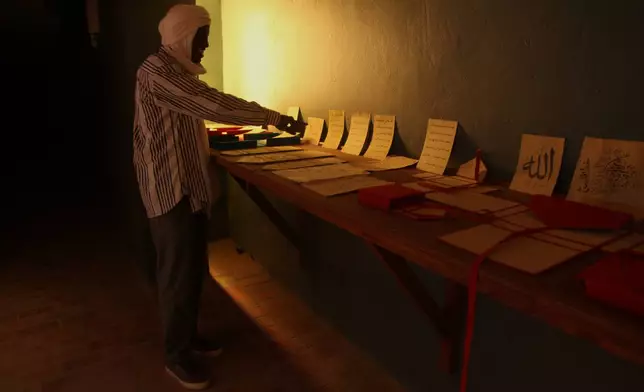 An employee of the Ahmed Baba Institute of Higher Islamic Studies and Research displays manuscripts at the exhibition hall in Timbuktu, Mali, Sept. 4, 2025. (AP Photo/Baba Ahmed)