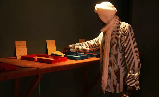 An employee of the Ahmed Baba Institute of Higher Islamic Studies and Research displays manuscripts at the exhibition hall in Timbuktu, Mali, Sept. 4, 2025. (AP Photo/Baba Ahmed)