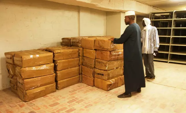 Abdoulaye Cissé, Left, an employee of the Ahmed Baba Institute of Higher Islamic Studies and Research, inspects crates containing manuscripts in Timbuktu, Mali, Sept. 4, 2025. (AP Photo/Baba Ahmed)