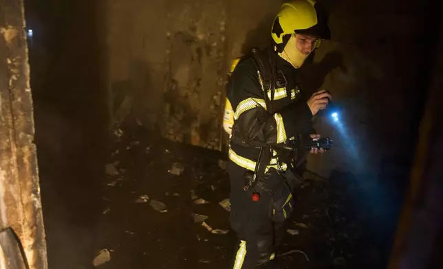 A rescuer searches for victims after a drone hit a residential building during Russia's night missile and drone attack in Kyiv, Ukraine, Saturday, Nov. 29, 2025. (AP Photo/Efrem Lukatsky)