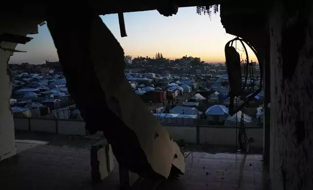 A makeshift tent camp for displaced Palestinians is seen through destruction in Deir al-Balah, central Gaza Strip, Wednesday, Nov. 26, 2025. (AP Photo/Abdel Kareem Hana)