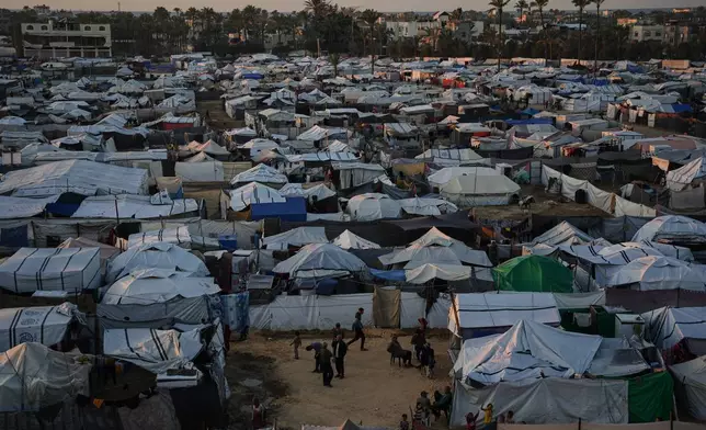 Displaced Palestinians gather outside a tent at a temporary camp in Deir al-Balah, central Gaza Strip, Wednesday, Nov. 26, 2025. (AP Photo/Abdel Kareem Hana)