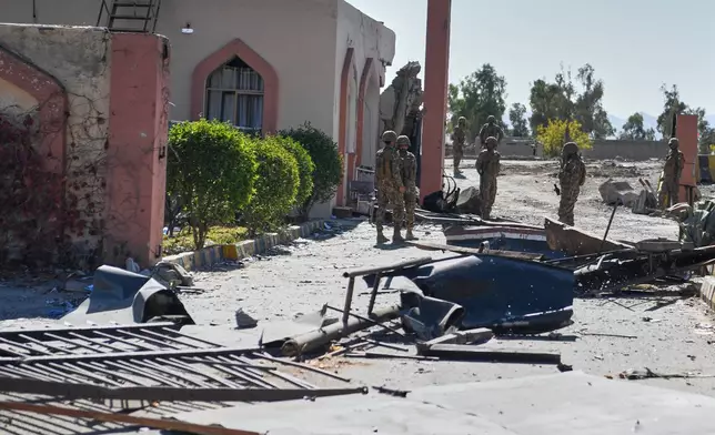 Army soldiers stand guard next to a damaged area at the main gate of an army-run cadet college that was assaulted by militants on Monday, in Wana, a city in the northwestern Pakistani district South Waziristan bordering with Afghanistan, Thursday, Nov. 13, 2025. (AP Photo/Ahsan Shahzad)