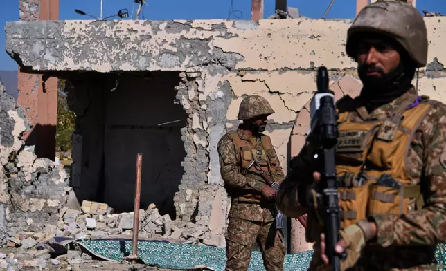 Army soldiers stands guard next to a damaged building of an army-run cadet college that was assaulted by militants on Monday, in Wana, a city in the northwestern Pakistani district South Waziristan bordering with Afghanistan, Thursday, Nov. 13, 2025. (AP Photo/Ahsan Shahzad)