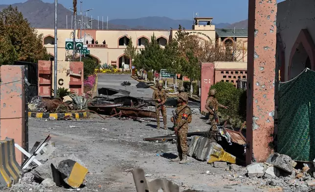 Army soldiers stand guard next to a damaged area at the main gate of an army-run cadet college that was assaulted by militants on Monday, in Wana, a city in the northwestern Pakistani district South Waziristan bordering with Afghanistan, Thursday, Nov. 13, 2025. (AP Photo/Ahsan Shahzad)
