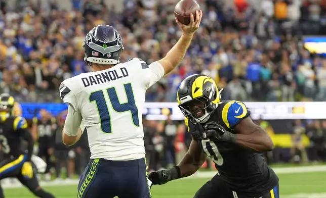 Seattle Seahawks quarterback Sam Darnold, let, passes while under pressure from Los Angeles Rams linebacker Byron Young during the second half of an NFL football game Sunday, Nov. 16, 2025, in Inglewood, Calif. (AP Photo/Gregory Bull)