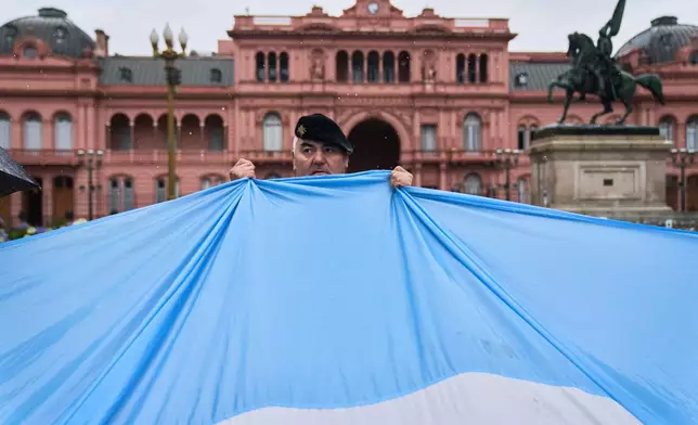 A retired military officer holds an Argentine flag in front of the presidential palace during a protest demanding the release of former servicemen accused of human rights violations during the last dictatorship, in Buenos Aires, Argentina, Saturday, Nov. 29, 2025. (AP Photo/Rodrigo Abd)