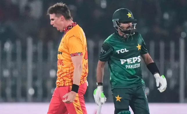 Zimbabwe's Brad Evans, left, celebrates after takin the wicket of Pakistan's Babar Azam, right, during the tri-series T20 cricket match between Pakistan and Zimbabwe, in Rawalpindi, Pakistan, Tuesday, Nov. 18, 2025. (AP Photo/Anjum Naveed)