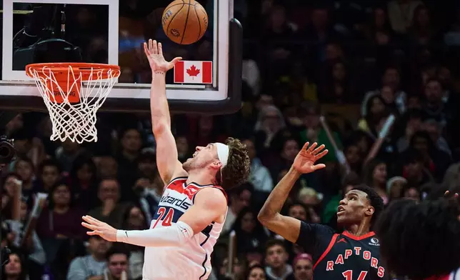 Washington Wizards' Corey Kispert (24) drives to the net past Toronto Raptors' Ja'Kobe Walter (14) during first half NBA basketball action in Toronto, Friday, Nov. 21, 2025. (Sammy Kogan/The Canadian Press via AP)