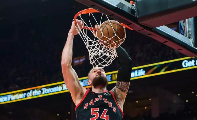 Toronto Raptors' Sandro Mamukelashvili (54) dunks against the Washington Wizards during first half NBA basketball action in Toronto, Friday, Nov. 21, 2025. (Sammy Kogan/The Canadian Press via AP)