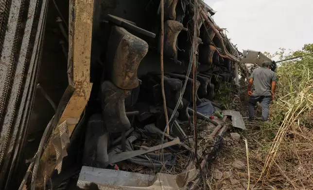 A man walks by a passenger bus after its deadly crash with another vehicle in Arequipa, Peru, Wednesday, Nov. 12, 2025. (AP Photo/Kiara Tapia)