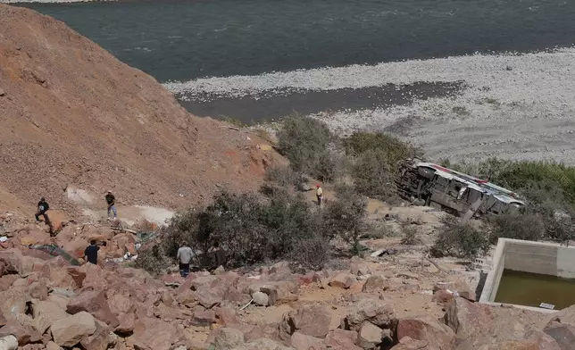 People walk by a passenger bus after its deadly crash with another vehicle in Arequipa, Peru, Wednesday, Nov. 12, 2025. (AP Photo/Kiara Tapia)