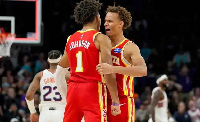 Atlanta Hawks forward Jalen Johnson (1) and Dyson Daniels, right, celebrate comeback win against Phoenix Suns during the second half of an NBA basketball game in Phoenix, Sunday, Nov. 16, 2025. Atlanta won 124-122. (AP Photo/Darryl Webb)