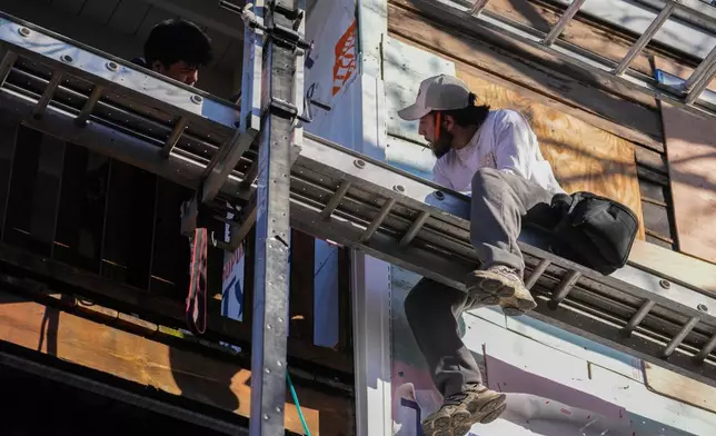 Uriel Villegas, top left, and his brother Julian work at the construction site where their older brother was taken by federal immigration agents in October, Tuesday, Nov. 18, 2025, in Chicago. (AP Photo/Erin Hooley)