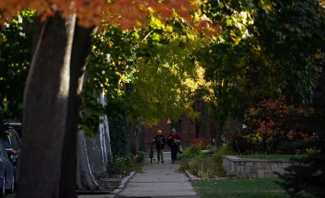 People walk along the street where federal immigration agents arrested three people in an October incident, including one of three brothers doing construction in the area and another 70-year-old man, Tuesday, Nov. 18, 2025, in the Old Irving Park neighborhood of Chicago. (AP Photo/Erin Hooley)