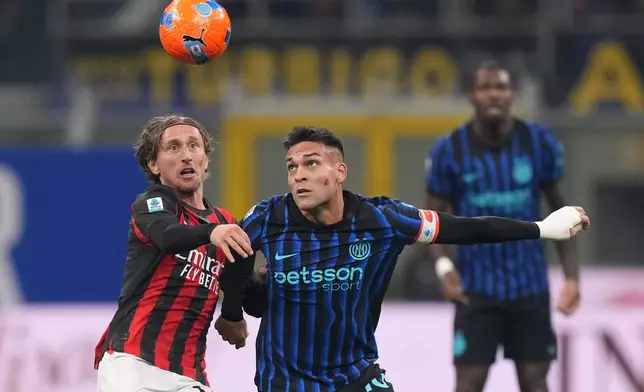 AC Milan's Luka Modric, left, and Inter Milan's Lautaro Martinez fight for the ball during the Serie A soccer match between Inter Milan and AC Milan in Milan, Italy, Sunday, Nov. 23, 2025. (AP Photo/Antonio Calanni)