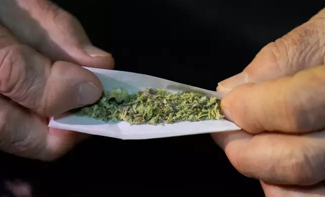 Miguel Laboy rolls a joint Friday, Nov. 14, 2025, in Brookline, Mass. (AP Photo/Robert F. Bukaty)