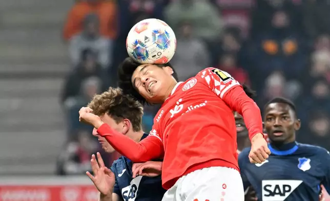 Mainz's Sota Kawasaki, right, heads the ball over Hoffenheim's Wouter Burger during the German Bundesliga soccer match between FSV Mainz 05 and TSG 1899 Hoffenheim in Mainz, Germany, Friday, Nov. 21, 2025. (Torsten Silz/dpa via AP)