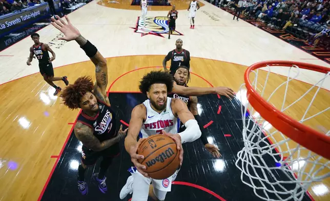 Detroit Pistons' Cade Cunningham, center, goes up for a shot against Philadelphia 76ers' Kelly Oubre Jr., left, and Trendon Watford during the second half of an NBA basketball game Sunday, Nov. 9, 2025, in Philadelphia. (AP Photo/Matt Slocum)