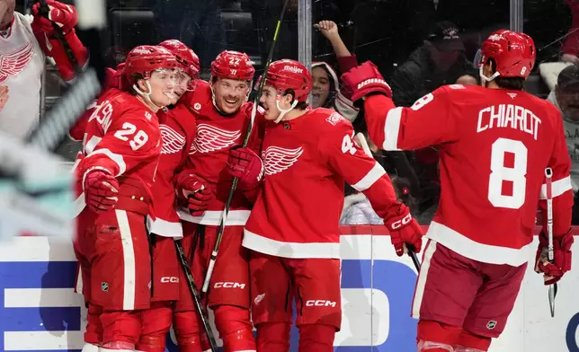 Detroit Red Wings center Nate Danielson, left, celebrates with teammates after scoring, a goal that on review was overturned on an off-side call, during the second period of an NHL hockey game against the Seattle Kraken, Tuesday, Nov. 18, 2025, in Detroit. (AP Photo/Ryan Sun)
