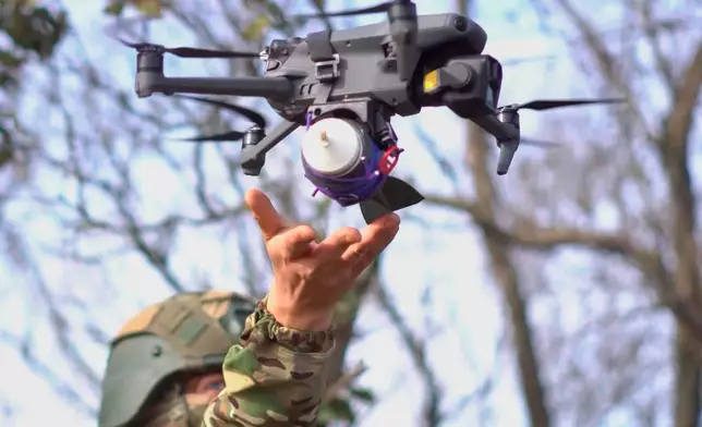 In this photo taken from a video provided by Russian Defense Ministry press service on Tuesday, Nov. 18, 2025, a Russian serviceman launches a drone with attached explosives at an undisclosed location in Ukraine. (Russian Defense Ministry Press Service via AP)