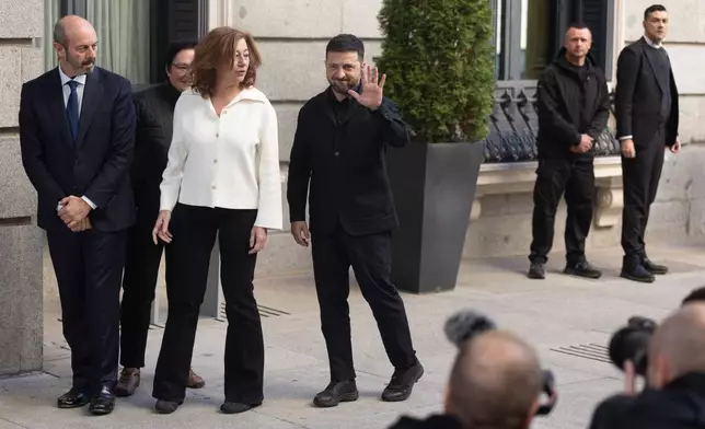 Ukrainian President Volodymyr Zelenskyy waves as he arrives at the Spanish parliament alongside Congress President Francina Armengol and Senate President Pedro Rollán, left, in Madrid, Spain, Tuesday, Nov. 18, 2025. (Eduardo Parra/Europa Press via AP) **SPAIN OUT**
