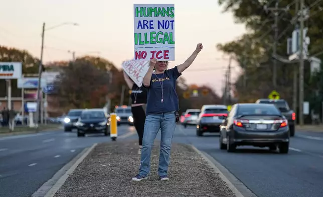 Protesters holds signs amidst the arrival of federal law enforcement, Monday, Nov. 17, 2025, in Charlotte, N.C. (AP Photo/Matt Kelley)