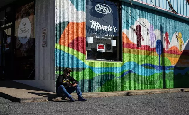 Manuel 'Manolo' Betancur sits outside of his bakery which is closed amidst federal law enforcement presence, Monday, Nov. 17, 2025, in Charlotte, N.C. (AP Photo/Matt Kelley)