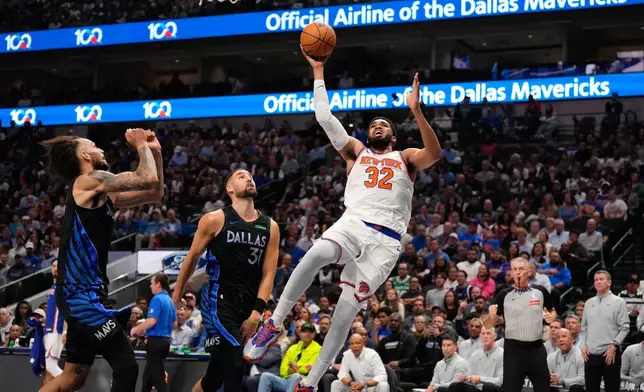 New York Knicks center Karl-Anthony Towns (32) shoots against Dallas Mavericks defenders Klay Thompson (31) and Dereck Lively II in the first half of an NBA basketball game Wednesday, Nov. 19, 2025, in Dallas. (AP Photo/Tony Gutierrez)