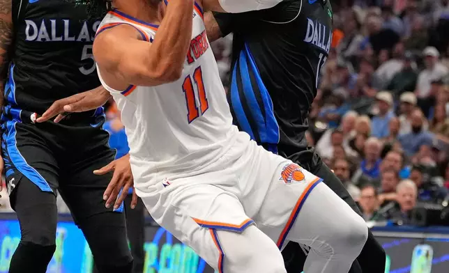 New York Knicks guard Jalen Brunson (11) drives against Dallas Mavericks defenders Naji Marshall (13) and D'Angelo Russell (5) in the first half of an NBA basketball game Wednesday, Nov. 19, 2025, in Dallas. (AP Photo/Tony Gutierrez)