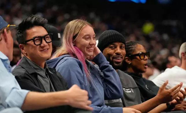 WNBA player Dallas Wings Paige Bueckers, center, sits court side in the first half of an NBA basketball game between the New York Knicks and Dallas Mavericks Wednesday, Nov. 19, 2025, in Dallas. (AP Photo/Tony Gutierrez)