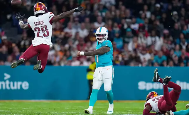 Washington Commanders safety Darnell Savage (25) tries to block a pass from Miami Dolphins quarterback Tua Tagovailoa (1) during the second half of an NFL football game between the Washington Commanders and the Miami Dolphins in Madrid, Spain, Sunday, Nov. 16, 2025. (AP Photo/Manu Fernandez)