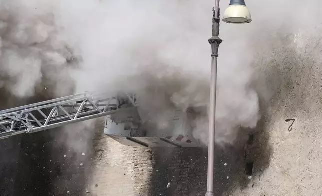 A cloud of debris from a second collapse is seen surrounding firefighters who were trying to rescue a worker after a medieval tower near the Roman Forum partially collapsed during renovation work, in Rome, Monday Nov. 3 2025. (Mauro Scrobogna/LaPresse via AP)