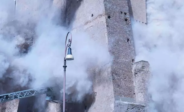 Firefighters work to rescue a construction worker from under the debris of the partially collapsed medieval Torre de Conti, meters away from the Colosseum in Rome, Monday, Nov. 3, 2025. (AP Photo/Domenico Stinellis)