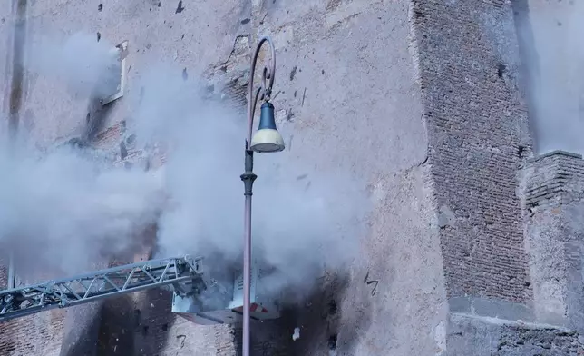 Firefighters work to rescue a construction worker from under the debris of the partially collapsed medieval Torre de Conti, meters away from the Colosseum in Rome, Monday, Nov. 3, 2025. (AP Photo/Domenico Stinellis)