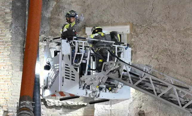 A firefighter gives a thumbs-up as rescuers pull a construction worker from under the debris of a medieval tower that was under renovation near the Roman Forum in Rome, Monday, Nov. 3, 2025, after it partially collapsed earlier in the morning. (Fabrizio Corradetti/LaPresse via AP)
