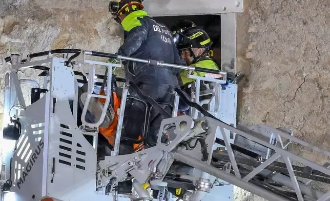 Firefighters pull a construction worker from under the debris of a medieval tower, which was under renovation near the Roman Forum in Rome, Monday, Nov. 3, 2025, after it partially collapsed in the morning. (Fabrizio Corradetti/LaPresse via AP)