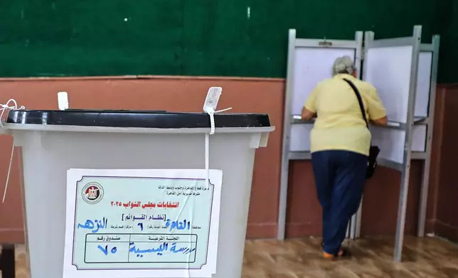 An Egyptian woman casts her ballot during the second phase of parliamentary elections in Cairo, Egypt, Monday, Nov. 24, 2025. (AP Photo/Khaled Elfiqi)