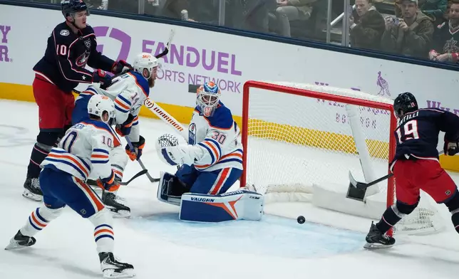 Columbus Blue Jackets center Adam Fantilli (19) reaches for the puck next to Edmonton Oilers goaltender Calvin Pickard in the first period of an NHL hockey game in Columbus, Thursday, Nov. 13, 2025. (AP Photo/Sue Ogrocki)