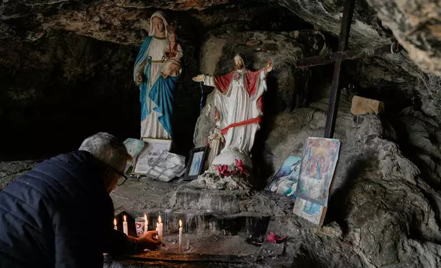 A man lights candles inside a cave that local tradition identifies as the site of Jesus Christ's first miracle, turning water into wine at a wedding feast, in the southern Lebanese village of Qana near the border with Israel, Lebanon, Sunday, Nov. 16, 2025. (AP Photo/Hassan Ammar)