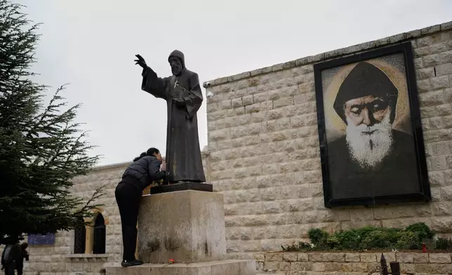 A worshipper kisses the statue of St. Charbel, a 19th-century Maronite monk, at his shrine in the northern village of Annaya, Lebanon, Saturday, Nov. 15, 2025. (AP Photo/Hassan Ammar)