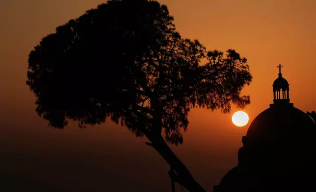 The sun sets behind the dome of the Melkite Greek Catholic Basilica of Saint Paul in Harissa, east of Beirut, Lebanon, Sunday, Nov. 9, 2025. (AP Photo/Hassan Ammar)