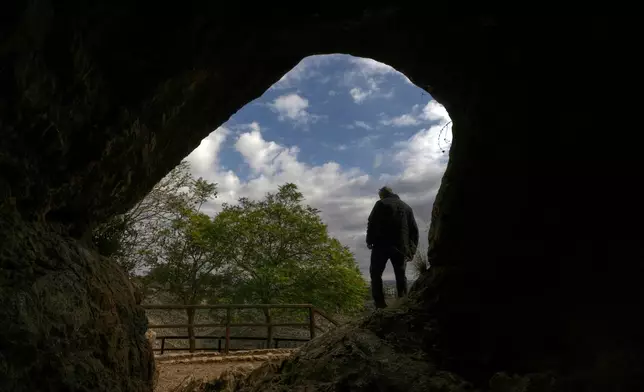 A man stands at the entrance of a cave that local tradition identifies as the site of Jesus Christ's first miracle, turning water into wine at a wedding feast, in the southern Lebanese village of Qana near the border with Israel, Lebanon, Sunday, Nov. 16, 2025. (AP Photo/Hassan Ammar)